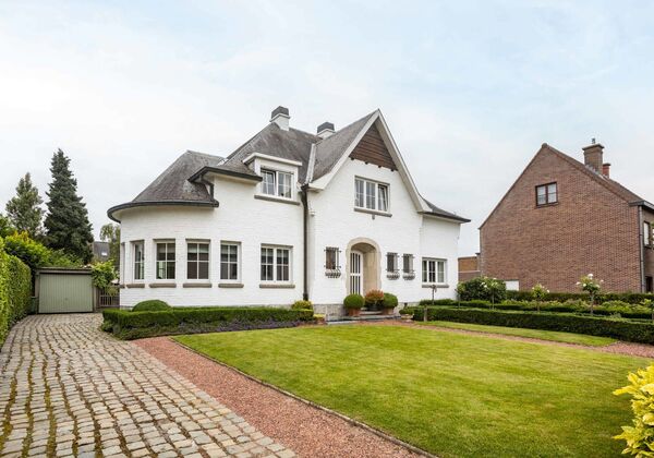 In een rustige buurt bevindt zich deze voormalige dokterswoning, een riante villa die ruimte, karakter en functionaliteit moeiteloos combineert. Met een perceel van maar liefst 1.100 m&sup2;, een volledig aangelegde tuin en een bijzonder praktische indeling i